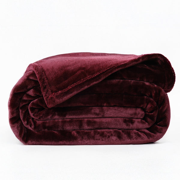 A folded dark red velvet AC blanket on a plain background.
